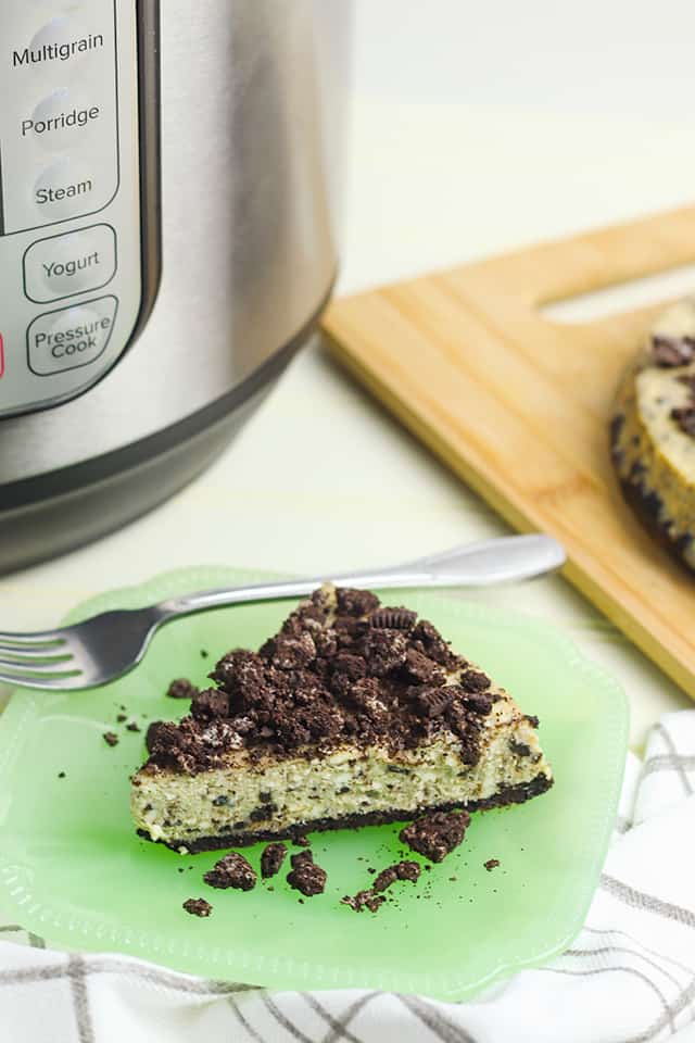 Instant Pot Oreo Cheesecake on a plate with a fork and pieces of oreo