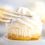 a fork slicing into the no bake mini lemon cheesecake with lemon curd squishing out