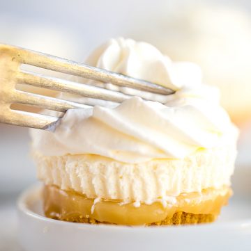 a fork slicing into the no bake mini lemon cheesecake with lemon curd squishing out