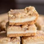 stack of snickerdoodle cheesecake bars on a polkadot fabric