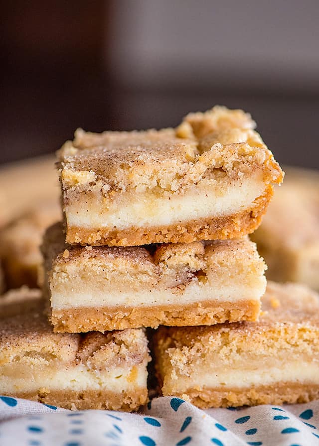 stack of snickerdoodle cheesecake bars on a polkadotted fabric