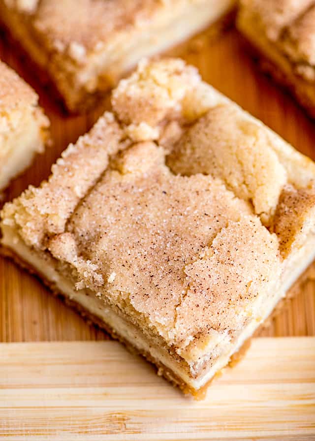 close up of a snickerdoodle cheesecake bar on a wooden cutting board