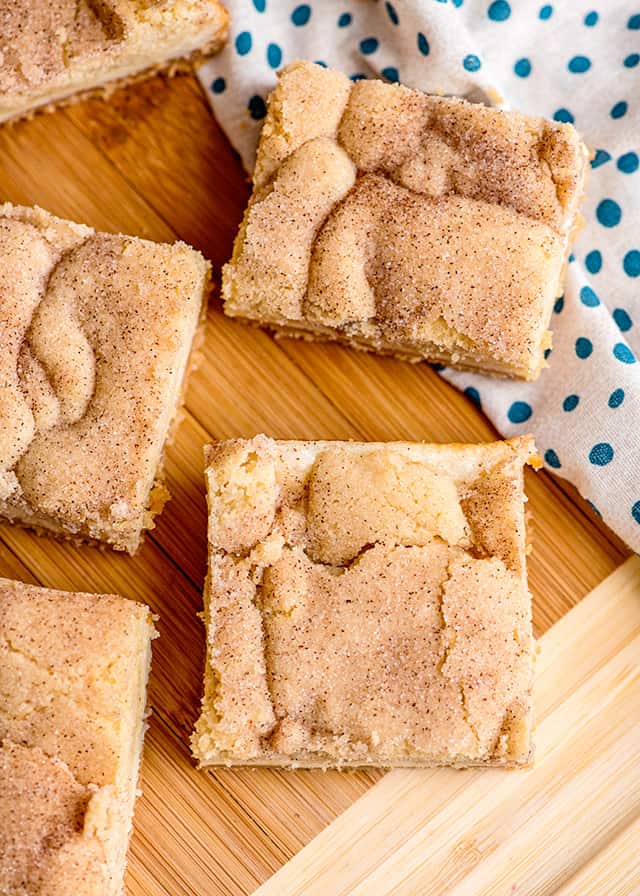 slices of snickerdoodle cream cheese bars on a cutting board with polka dot fabric