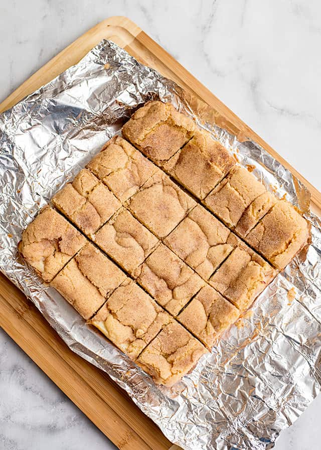 slices of snickerdoodle cheesecake bars on foil and cutting board