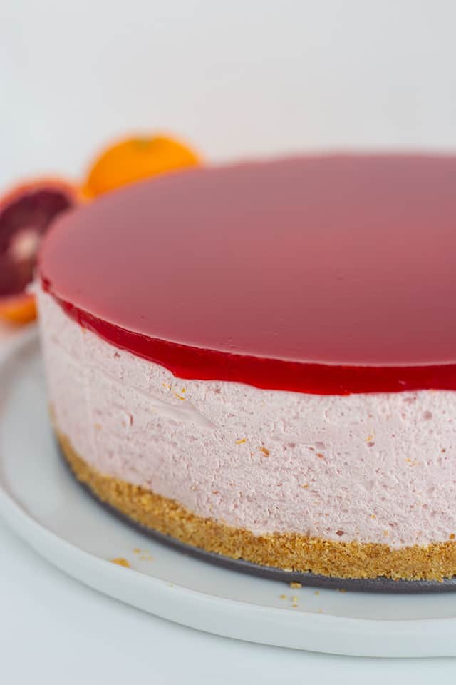 whole blood orange cheesecake on a white platter