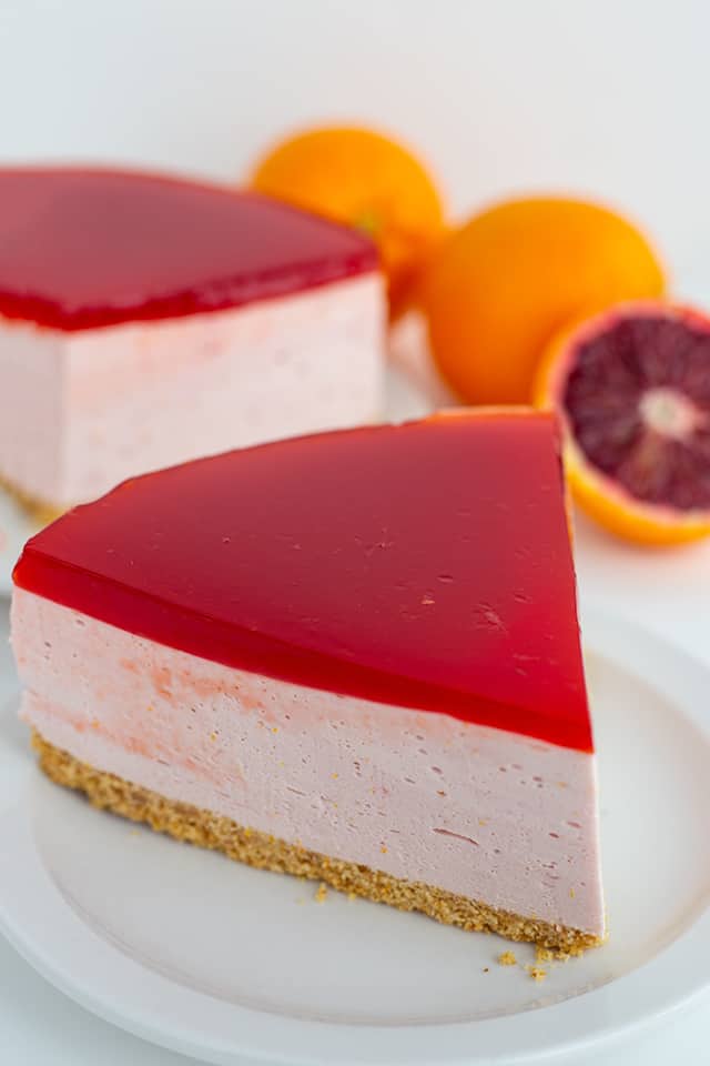 slice of blood orange cheesecake on a white plate with a sliced orange