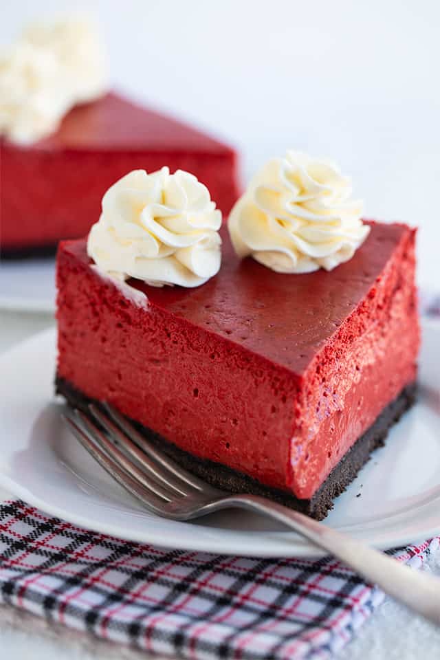 slice of red velvet cheesecake on a white plate with fork