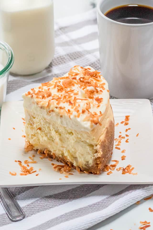 slice of instant pot cheesecake on a white square plate with toasted coconut