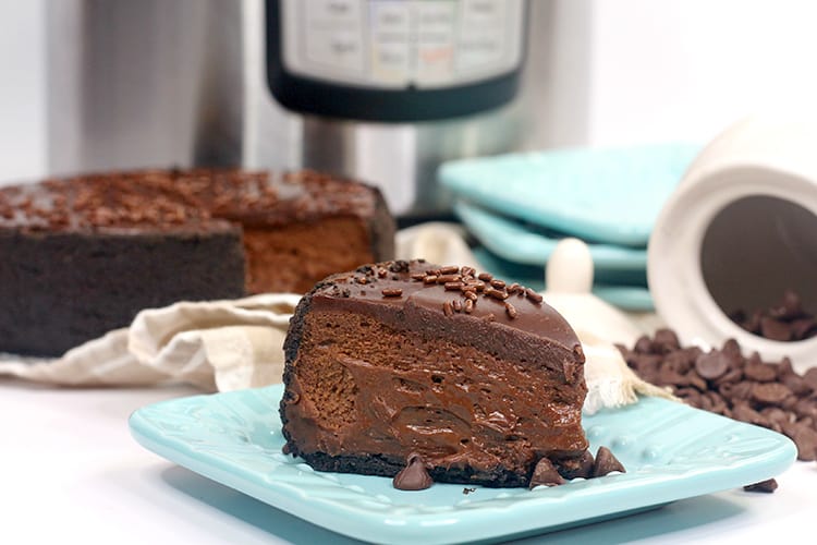 chocolate cheesecake on a blue square plate with an instant pot behind it