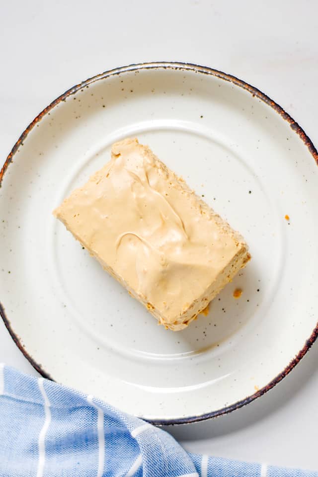 overhead photo of coffee cheesecake bars on a white plate with a blue striped linen