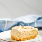 slice of dalgona coffee cheesecake bars on a white dessert plate with blue linen