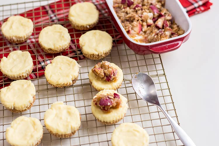 cheesecakes on a wire rack with the a spoon and crumble in a dish