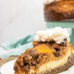 slice of pecan pie pumpkin cheesecake on a white plate with a blue charger