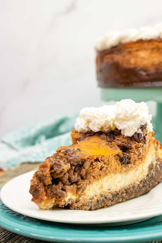 slice of pecan pie pumpkin cheesecake on a white plate with a blue charger