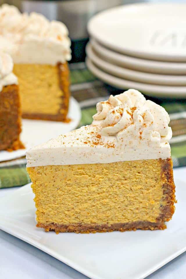 Close up of sliced pumpkin cheesecake with the rest of the cheesecake behind it