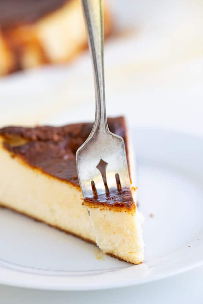 slice of cheesecake on a white plate with a fork in it