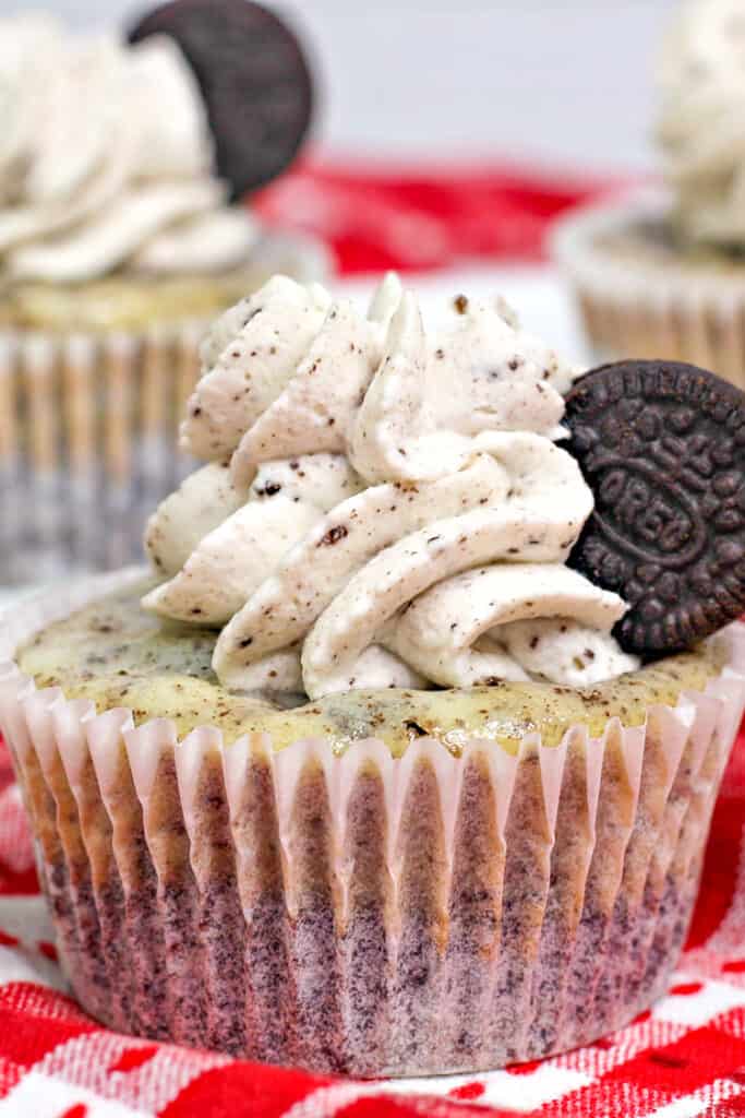 close up of oreo cheesecake on a red fabric with other cheesecakes behind it