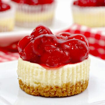 mini cheesecake on a square white plate with a red and white checked linen behind it