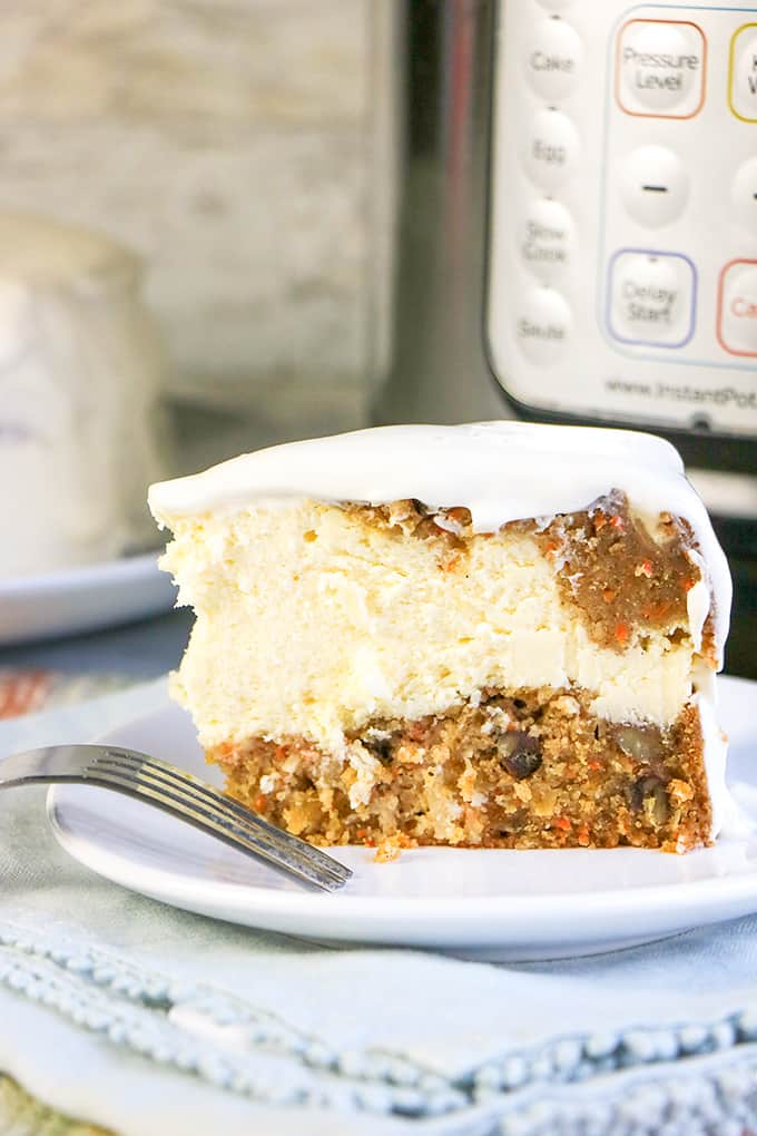 carrot cake cheesecake on a white plate with a fork on it with a blue fabric under it