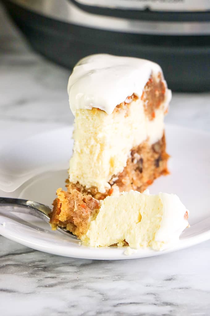 cheesecake on a white plate with a fork full of cheesecake on it