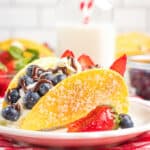 large cheesecake tacos on a white plate with a red and white checkered fabric under it