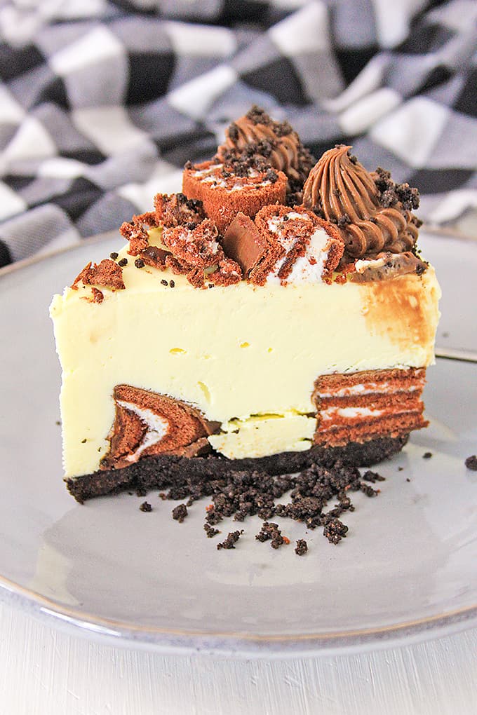 a slice of cheesecake on a gray plate with oreo crumbs beside the slice