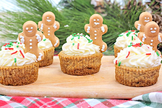 mini christmas cheesecakes on a cutting board with a garland behind the cheesecakes