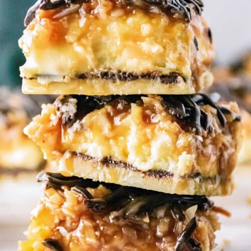 three samoa cheesecake bars stacked on a marble table